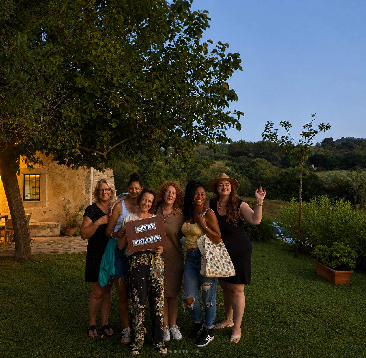 The group together in the garden at dusk with the Casa Romana sign