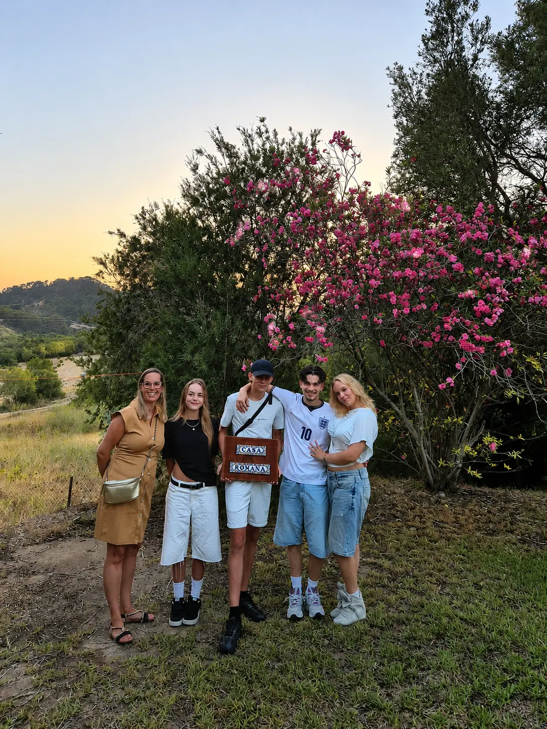 A family standing together at sunset by the Casa Romana sign